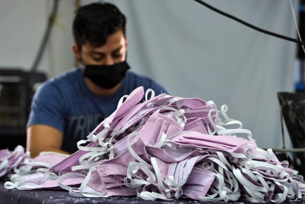 Personnel of the Military Industry of the Armed Forces of Honduras, makes face masks for members of the Health sector who are in the front line in the fight against the novel coronavirus, COVID-19, in Tegucigalpa, on April 1, 2020. - The World Health Organization said Wednesday it was concerned about the recent 'rapid escalation' and global spread of the new coronavirus pandemic. (Photo by Orlando SIERRA / AFP)