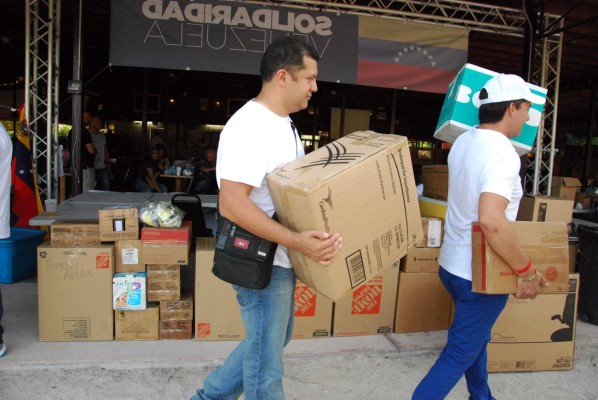 People bring supplies to send to protesters in Venezuela at the 'Solidaridad Venezuela' event in Hialeah, Florida on May 13, 2017. Venezuela is mired in an economic crisis that has caused shortages of food, medicine and other basics in the oil-rich country. A total of 38 people have died in street unrest since protests first broke out on April 1. Hundreds more have been injured. / AFP PHOTO / Jose Caruci