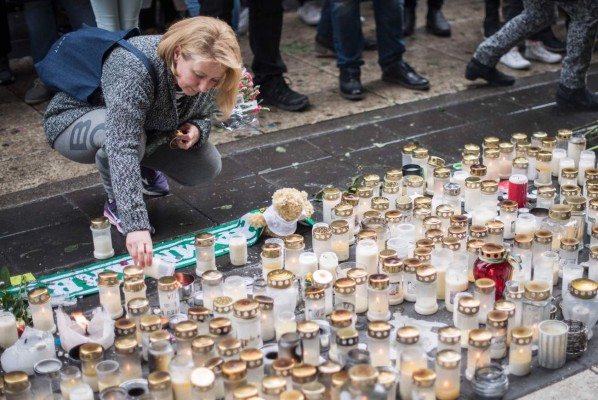 A woman lays a candle to commemorate the victims of Friday's terror attack at a makeshift memorial near the site where a truck drove into Ahlens department store in Stockholm, Sweden, on April 10, 2017.Four people died and fifteen were injured when a truck plunged into a crowd at a busy pedestrian street in the Swedish capital on April 7, 2017. / AFP PHOTO / Jonathan NACKSTRAND