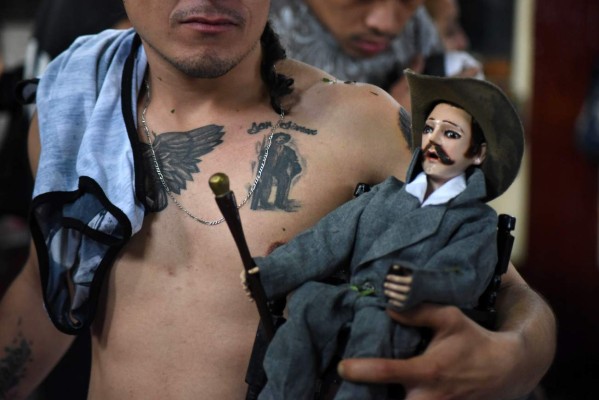 A woman holds a doll depicting folk saint Maximon (or Simon), during the Saint Simon celebrations in San Andres Itzapa, Guatemala, on October 28, 2019. - Thousands believe that the saint helps people find work, solves family problems and cures illnesses. (Photo by ORLANDO ESTRADA / AFP)
