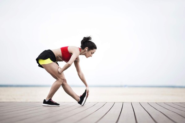 Young woman stretching on the beach after running, Dubai, Jumeirah Beach