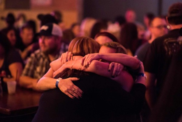 Women hug at a fundraiser for victims of the Las Vegas massacre and their families, October 4, 2017 at Stoney's Rockin' Country bar and country music venue in Las Vegas, Nevada. Country music is what brought together the huge crowd targeted in the Las Vegas massacre and it was what brought hundreds of them back together again in a show of strength and solidarity. Five days after the worst mass shooting in modern American history little is known about the motive of the killer who left 58 dead and over 500 injured when he rained hundreds of rounds into a crowd at a country music festival. / AFP PHOTO / Robyn Beck