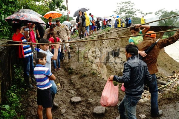 Pobladores de Omoa intentan cruzar por el puente que colapsó ayer en Tegucigalpita, Cortés.