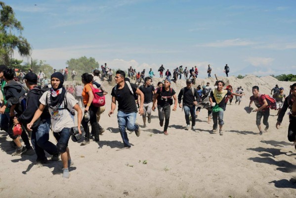 Central American migrants - mostly Hondurans travelling in caravan to the US- run after crossing the Suchiate River, the natural border between Tecun Uman in Guatemala and Ciudad Hidalgo in Mexico, on January 20, 2020. - Hundreds of Central Americans from a new migrant caravan tried to enter Mexico by force Monday by crossing the river that divides the country from Guatemala, prompting the National Guard to fire tear gas, an AFP correspondent said. (Photo by Johan ORDONEZ / AFP)