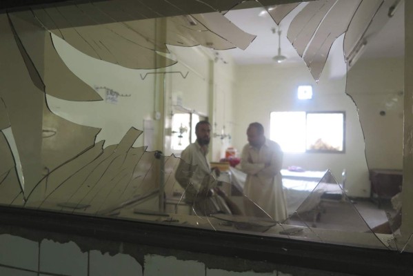 Dos hombres observan al fotógrafo a través de un cristal roto tras un ataque con bomba, hoy en un hospital de Quetta (Pakistán). EFE