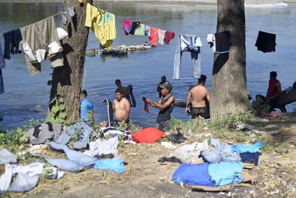 Central American migrants -mostly Hondurans heading in a caravan for the US- wash clothes in the Suchiate river, on which bank they spent the night, in Tecun Uman, Guatemala, on the border with Ciudad Hidalgo, Mexico, on January 21, 2020. - Some 500 Central Americans, from the so-called '2020 Caravan', crossed Monday from Guatemala to Mexico, but over 400 were intercepted when National Guardsmen fired tear gas at them. (Photo by Johan ORDONEZ / AFP)