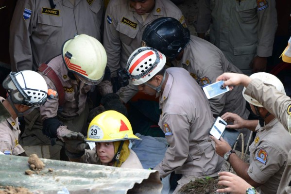Rescuers carry the bodies of a woman and her son buried by a landslide, caused by the heavy rains at the 'Oscar A. Flores' neighbourhood in the outskirts of Tegucigalpa on October 8, 2016. / AFP PHOTO / ORLANDO SIERRA