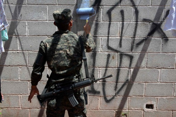 Momentos en que los militares pintaban las paredes para borrar la simbología de los pandilleros.