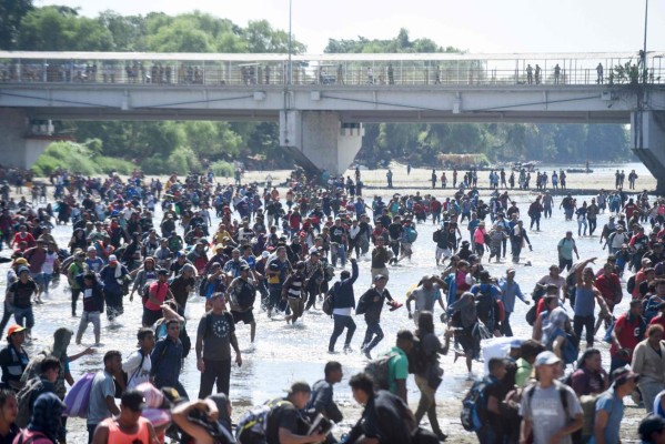 Cientos de migrantes centroamericanos que quieren llegar a Estados Unidos intentaban cruzar este lunes a México desde Guatemala mientras eran contenidos a golpe de gases lacrimógenos por guardias nacionales mexicanos en el río Suchiate. AFP