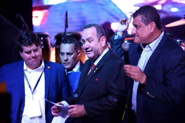 Guatemalan presidential candidate for the Vamos (Let's Go) party Alejandro Giammattei (C) speaks to supporters next to running mate Guillermo Castillo (R) at the party headquarters in Guatemala City on August 11, 2019 after the run-off presidential election. - Giammattei declared victory in Sunday's run-off election in Guatemala, holding a major lead with the results from more than 90 percent of polling stations counted. (Photo by JOHAN ORDONEZ / AFP)