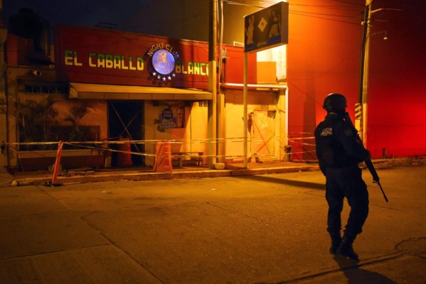 A police officer stands guard outside Caballo Blanco bar (White Horse bar) where 23 people were killed by a fire in Coatzacoalcos, Veracruz State, Mexico, on August 28, 2019. - At least 23 people were killed and 13 badly wounded in a fire which broke out Tuesday night at the bar as is being investigated as an attack, authorities said Wednesday. The state of Veracruz is a flashpoint in the bloody turf wars between Mexico's rival drug cartels. (Photo by VICTORIA RAZO / AFP)
