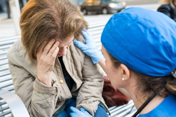 Female doctor assisting a senior woman in the street