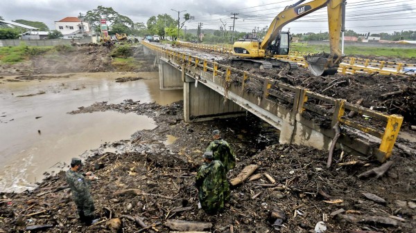 A backhoe makes cleaning works after the passage of tropical storm Eta near members of the armed forces in La Lima municipality, Cortes department, northern Honduras, on November 16, 2020, ahead of Hurricane Iota. (Photo by Wendell ESCOTO / AFP)