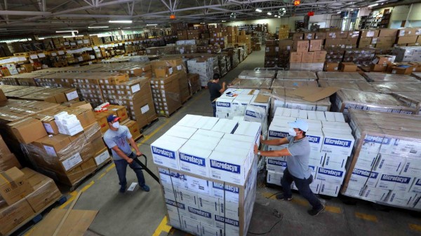 AME4829. TEGUCIGALPA (HONDURAS), 06/06/2020.- Fotografía cedida este sábado, por la Casa Presidencial que muestra a empleados públicos mientras trabajan en una bodega donde mantienen almacenado medicamentos MAIZ y CATRACHO para el tratamiento del coronavirus y que será distribuido en centros de salud del país. El maíz, alimento básico del hondureño desde los tiempos de los mayas, tiene ahora en la medicina una nueva 'variedad', la 'MAIZ', una terapia que, con la de 'Catracho', son una esperanza de vida para los que recién han contraído la COVID-19, enfermedad que desde marzo ha causado 248 muertos en Honduras. EFE/ Casa Presidencial SOLO USO EDITORIAL NO VENTAS