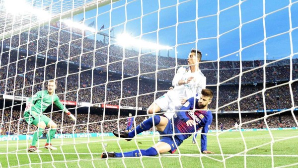 Real Madrid's Portuguese forward Cristiano Ronaldo falls on Barcelona's Spanish defender Gerard Pique as he scored a goal during the Spanish league football match between FC Barcelona and Real Madrid CF at the Camp Nou stadium in Barcelona on May 6, 2018. / AFP PHOTO / LLUIS GENE