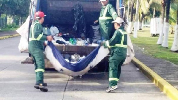 Hombres recogen basura con Bandera Nacional de Honduras