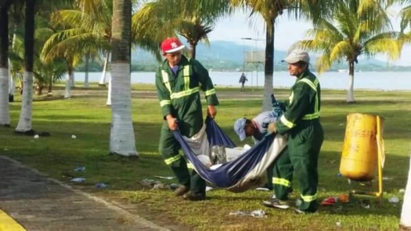 Hombres recogen basura con Bandera Nacional de Honduras