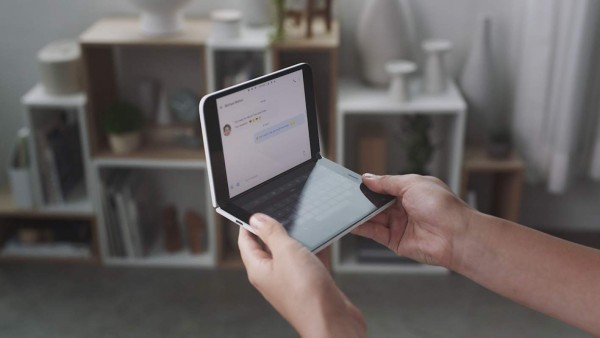 This handout photo obtained October 2, 2019 courtesy of Microsoft shows a woman looking at a new dual-screen device Surface Duo. - Microsoft on October 2, 2019 unveiled Surface tablet computers with twin-screens that opened like books, and a notepad-sized version that put it back in the smartphone game.Surface Duo was touted as the first device in the line-up to fit into a pants pocket, with two 'paper-thin' 5.6-inch screens that unfold and work in harmony with a specially tailored Windows operating system. Duo handled telephone calls, as well as applications designed to run on Google-backed Android mobile software, which powers most of the world's smartphones.'You are going to talk about it as a phone, and I get that,' Microsoft chief product officer Panos Panay said of Duo at a Surface event in New York City. (Photo by HO / Microsoft / AFP) / RESTRICTED TO EDITORIAL USE - MANDATORY CREDIT 'AFP PHOTO / MICROSOFT/HANDOUT' - NO MARKETING - NO ADVERTISING CAMPAIGNS - DISTRIBUTED AS A SERVICE TO CLIENTS