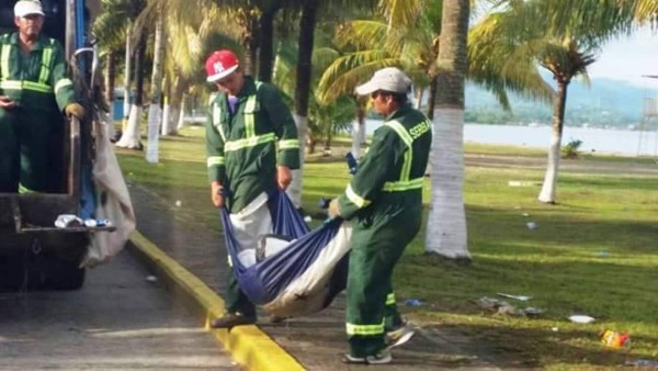 Hombres recogen basura con Bandera Nacional de Honduras