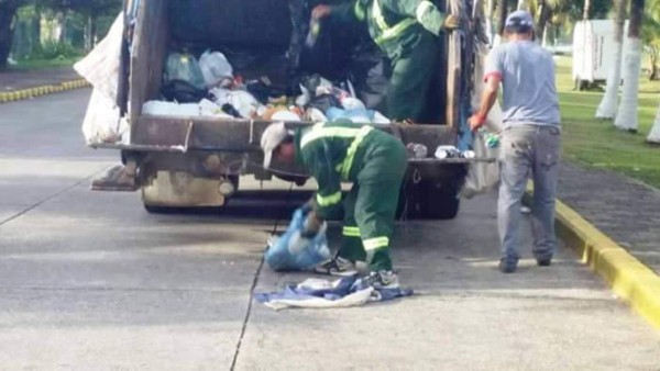 Hombres recogen basura con Bandera Nacional de Honduras