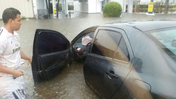 Un hombre observa cómo su vehículo se quedó varado producto de las lluvias en las cercanías de un centro comercial.