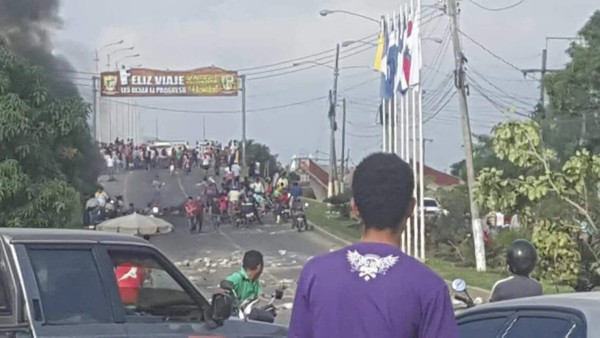 Esta imagen corresponde a la toma en el puente de La Democracia, salida a San Pedro Sula; la posta policial que fue quemada es la de la colonia Berlín, salida a Tela.