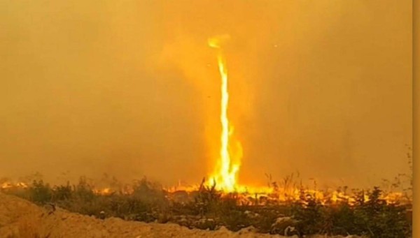 Bomberos canadienses luchan por controlar sus mangueras en un tornado de fuego