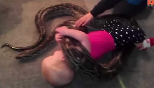 Impresiona ver a la bebé jugar con la pitón. Foto YouTube.