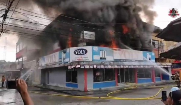 El momento cuando el personal del Cuerpo de Bomberos controla el incendio en un local del centro de Tela, Atlántida.