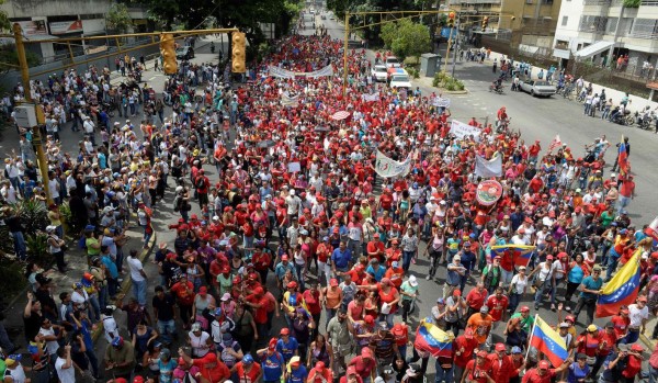 Demonstrators in support of President Nicolas Maduro's government(C in red) march towards downtown Caracas while anti Government protesters(at L) shout them slogans on April 19, 2017.Venezuela braced for rival demonstrations Wednesday for and against President Nicolas Maduro, whose push to tighten his grip on power has triggered waves of deadly unrest that have escalated the country's political and economic crisis. / AFP PHOTO / FEDERICO PARRA