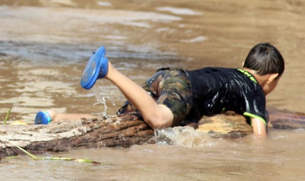 Niños hondureños se bañan en aguas estancadas por Iota