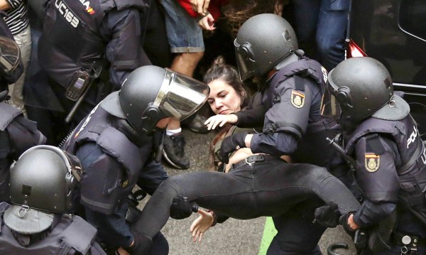 GRA065. BARCELONA, 01/10/2017.- Agentes antidisturbios de la Policía Nacional que han formado un cordón de seguridad trasladan a una joven frente al colegio Ramón Llull de Barcelona. Policía Nacional y Guardia Civil han desplegado a sus agentes en varios colegios electorales de Barcelona para impedir el referéndum del 1-O, suspendido por el Tribunal Constitucional (TC), lo que ha originado momentos de tensión y algún forcejeo con las personas concentradas ante los locales. EFE/Alberto Estévez