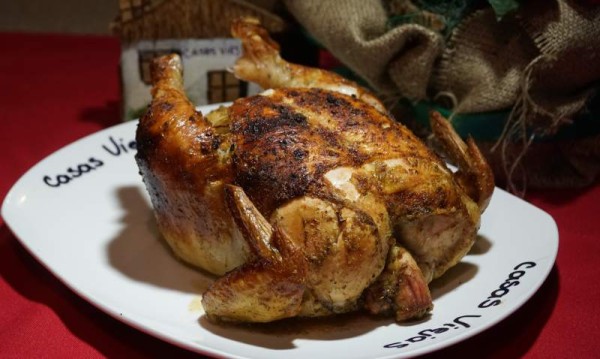 Pollo horneado lleva varias hierbas y se elabora en un horno tradicional de barro con leña, logrando un sabor ahumado bien natural.