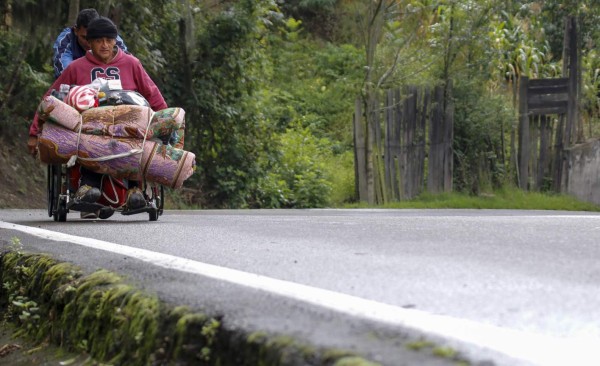 Venezuelan migrant Jefferson Alexis pushes his father Jose Agustin Lopez's wheelchair along the road linking Cucuta and Pamplona, in Norte de Santander Department, Colombia, on September 15, 2018.Lopez started an odyssey to Bogota looking for the medicines he could not gey in Venezuela. / AFP PHOTO / SCHNEYDER MENDOZA