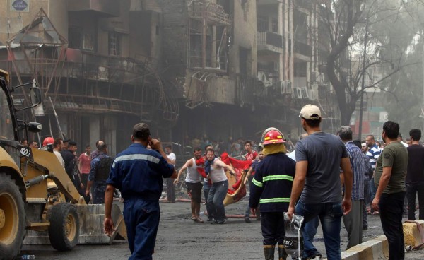 Iraqis evacuate a body from the site of a suicide car bombing claimed by the Islamic State group on July 3, 2016 in Baghdad's central Karrada district.The blast, which ripped through a street in the Karrada area where many people go to shop ahead of the holiday marking the end of the Muslim fasting month of Ramadan, killed at least 75 people and also wounded more than 130 people, security and medical officials said. The Islamic State group issued a statement claiming the suicide car bombing, saying it was carried out by an Iraqi as part of the group's 'ongoing security operations'. / AFP PHOTO / SABAH ARAR