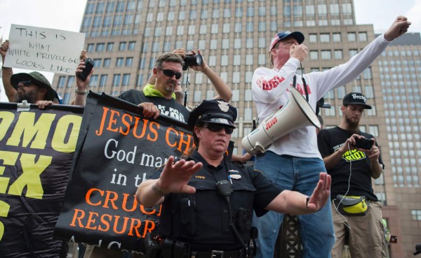 A police officer tries to keep seperation between anti-Trump protesters and pro-Trump supporters(rear)outside the Republican National Convention on July 18, 2016 in Cleveland, Ohio.Thousands of delegates descend on a tightly secured Cleveland arena for the opening of the Republican National Convention, with Donald Trump's wife playing character witness as the tough-talking mogul seeks to lock up his party's presidential nomination. / AFP PHOTO / Andrew CABALLERO-REYNOLDS