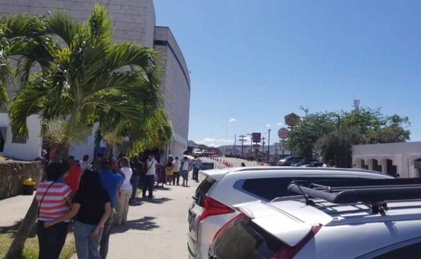 Bajo el inclemente sol y enormes filas obligan a esperar a viajeros en el Toncontín