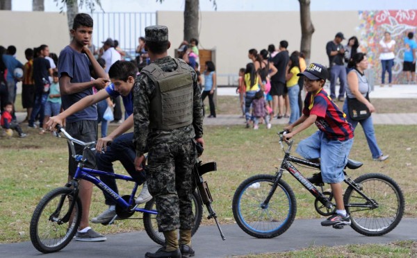 Rodeados de militares, niños hondureños juegan en un parque a prueba de pandilleros