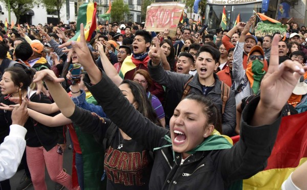 Supporters of Bolivia's main opposition presidential candidate, former president (2003-2005) Carlos Mesa, shout slogans against supporters of president and candidate Evo Morales, as both groups gather outside the hotel where the Supreme Electoral Tribunal has its headquarters to count the election votes, in La Paz, on October 21, 2019. - Evo Morales, seeking a controversial fourth term, led Bolivia's presidential election race Sunday but faces a historic second round run-off against Mesa, partial results showed. Morales had 45 percent of the vote to Mesa's 38 percent, the Supreme Electoral Tribunal announced, with most of the votes counted. (Photo by Aizar RALDES / AFP)