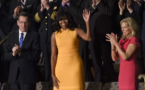 US First Lady Michelle Obama (C) waves, as Jill Biden (R) wife of US Vice President Joe Biden looks on before the arrival of US President Barack Obama before the State of the Union Address during a Joint Session of Congress at the US Capitol in Washington, DC, January 12, 2016. Barack Obama will give his final State of the Union address, perhaps the last big opportunity of his presidency to sway a national audience and frame the 2016 election race. AFP PHOTO / SAUL LOEB