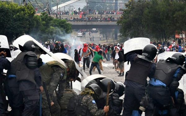 Supporters of Honduran presidential candidate for the Opposition Alliance against the Dictatorship coalition, Salvador Nasralla, clash with soldiers and riot police near the Electoral Supreme Court (TSE), as the country waits for the final results of the week-end's presidential election, in Tegucigalpa, on November 30, 2017. Honduran President Juan Orlando Hernandez edged closer Thursday to winning a tense election as rival Nasralla said he will not recognize the result, claiming fraud. In a vote count dogged by computer failures and claims by Nasralla that the president was stealing the election, Hernandez had overturned a 5.0 percent deficit by early Thursday to lead by just 1.0 percent with 90 percent of the votes counted. / AFP PHOTO / Orlando SIERRA