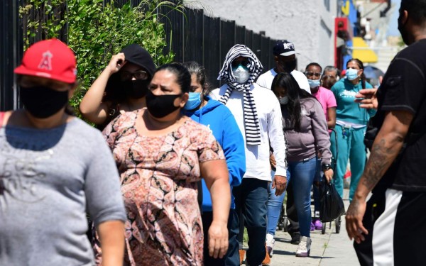 People wear their face masks waiting in line for an emergency food distribution at the 88th Street Temple Church of God in Christ on April 14, 2020 in Los Angeles, California, during the coronavirus pandemic. (Photo by Frederic J. BROWN / AFP)