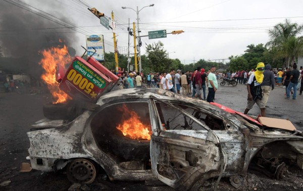 A car set on fire by supporters of Honduran presidential candidate for the Opposition Alliance against the Dictatorship coalition Salvador Nasralla during protests demanding the final results of the weekend&#39;s presidential election, burns in Tegucigalpa, on December 1, 2017. Fresh clashes broke out Friday between riot police and opposition supporters in Honduras, as the counting of votes in a cliff-hanging presidential election rolled into a fifth day. Police said at least 12 civilians were injured, some by gunfire, after violence erupted in several parts of the country -- sparked by opposition candidate Salvador Nasralla claiming fraud and calling his supporters onto the streets. / AFP PHOTO / JORDAN PERDOMO