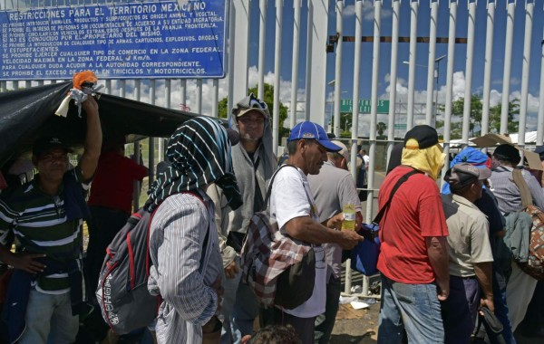 Migrantes hondureños esperan en puente fronterizo la oportunidad de entrar a México