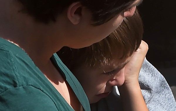 A woman hugs her crying child after he and other North Park Elementary School students were released to their guardians following a shooting at the elementary school which left two adults and one child dead, April 10, 2017 at Cajon High School in San Bernardino California. A gunman opened fire at an elementary school in the California city of San Bernardino, killing one woman and wounding two students before turning the gun on himself, police said. The students were airlifted to a local hospital where their conditions were described as critical. / AFP PHOTO / Robyn Beck
