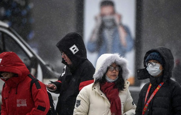 Tourists - with the one wearing a medical mask - walk along a street in Moscow on January 29, 2020. - Russia's Urals Airlines suspended some services to Europe including Paris and Rome due to the outbreak of the deadly coronavirus. The airline, based in the Urals city of Yekaterinburg, was halting flights to Munich, Paris and Rome as well as the Japanese city of Sapporo until the end of winter, it said in a statement. Those flights had been affected because they are popular with Chinese tourist groups. (Photo by Alexander NEMENOV / AFP)