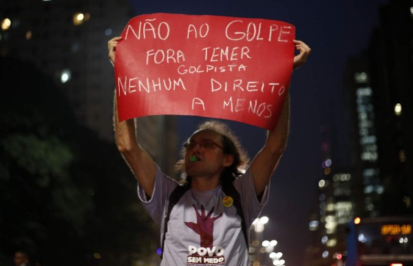 A supporter of Brazilian President Dilma Rousseff holds a sign reading 'No to the coup. Temer out' during a protest against her impeachment in Sao Paulo, Brazil on May 9, 2016. The impeachment of Brazilian President Dilma Rousseff was thrown into confusion when Waldir Maranhao, the interim speaker of the lower house of Congress annulled on May 9, 2016 an April vote by lawmakers to launch the process. He wrote in an order that a new vote should take place on whether to impeach Rousseff. / AFP PHOTO / Miguel Schincariol