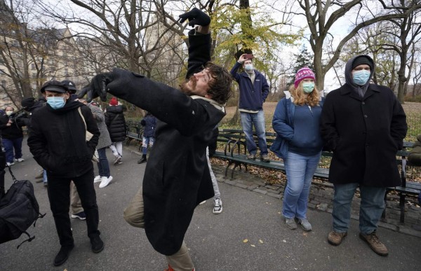 Peole dance as mourners gather on the 40th anniversary of John Lennon's death, at Strawberry Fields, in Central Park to honor the late Beatles star in New York on December 8, 2020. (Photo by TIMOTHY A. CLARY / AFP)
