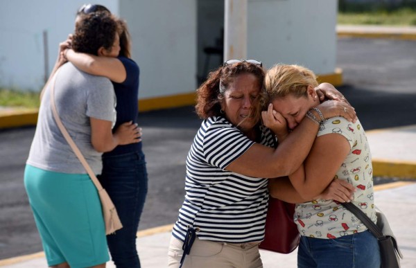 Relatives and friends of victims embrace each other outside the General Prosecutor's Office of the state of Veracruz on August 28, 2019 in Coatzacoalcos, where at least 26 people were killed and 11 people badly wounded after gunmen trapped revellers inside the Caballo Blanco bar (White Horse bar) and started a raging fire on the eve. - President Andres Manuel Lopez Obrador condemned the 'shameful' attack and said federal authorities would investigate evidence it may have stemmed from collusion between local authorities and organized crime. (Photo by VICTORIA RAZO / AFP)