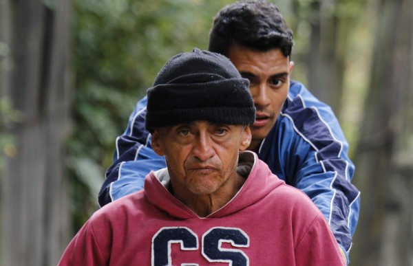 Venezuelan migrant Jefferson Alexis pushes his father Jose Agustin Lopez's wheelchair along the road linking Cucuta and Pamplona, in Norte de Santander Department, Colombia, on September 15, 2018.Lopez started an odyssey to Bogota looking for the medicines he could not gey in Venezuela. / AFP PHOTO / SCHNEYDER MENDOZA